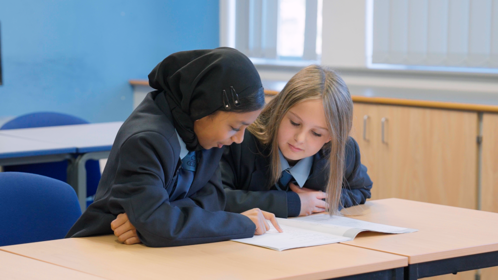 two students at a desk reading during partner practice
